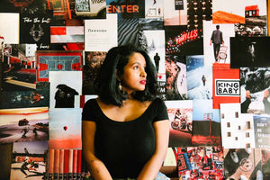 Lady in black top with aesthetic collage kit posters behind her on the wall