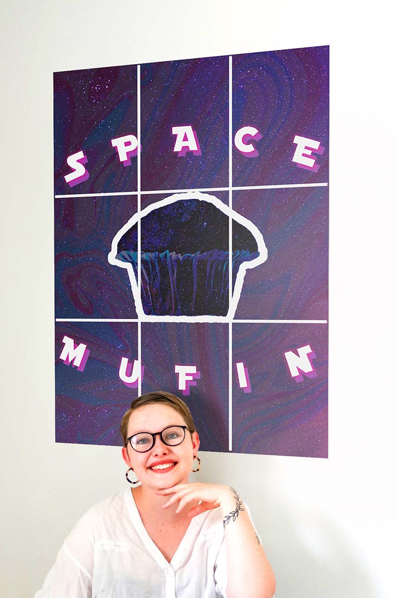 Short hair girl smiling with muffin block kit poster behind her on the wall