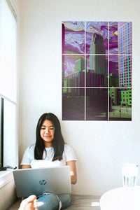 Girl working on her laptop next to a big block kit poster on the wall of a city with purple skies