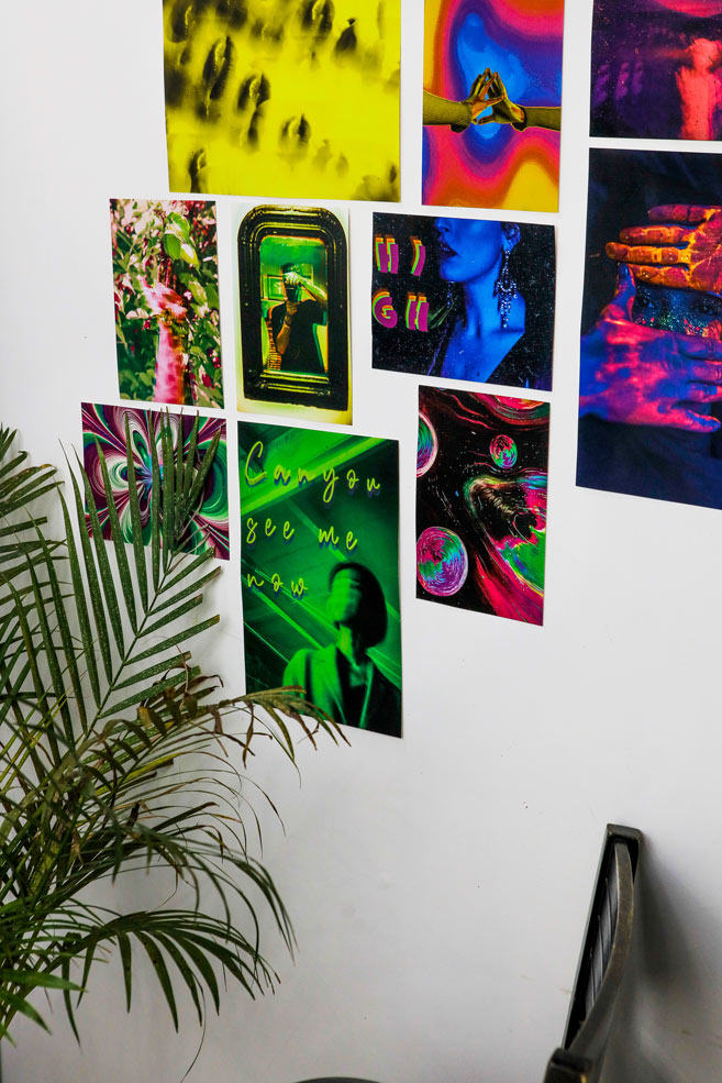 Trippy mini kit posters on a wall  next to a house plant and a chair