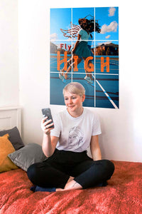 girl taking a selfie on her bed with big poster on her wall